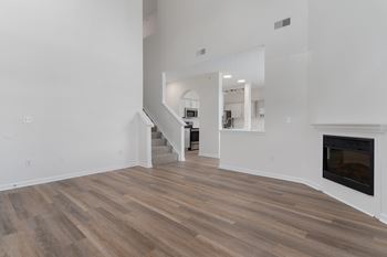 A living room with white walls and a fireplace and wooden floors